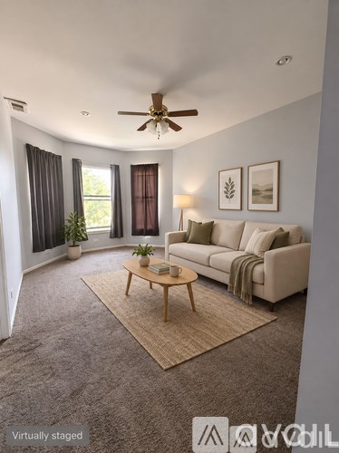 A living room with a couch, coffee table, and ceiling fan.