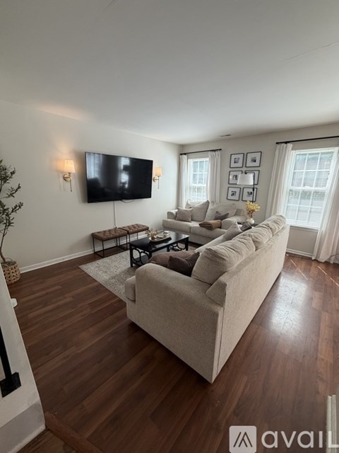 A living room with a couch, a coffee table, and a television mounted on the wall.