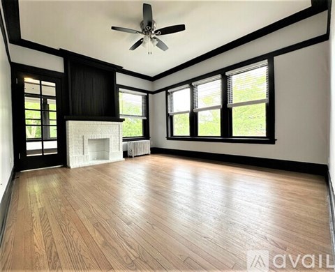 A spacious room with wooden flooring and a ceiling fan.