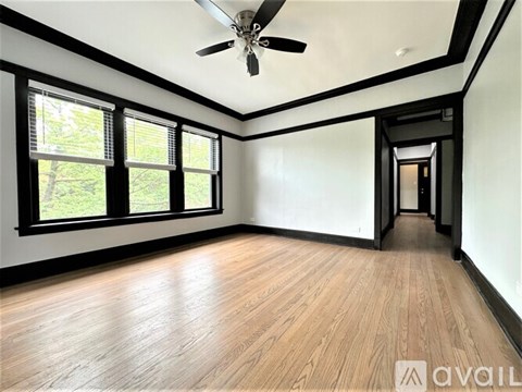 A room with a ceiling fan and wooden flooring.