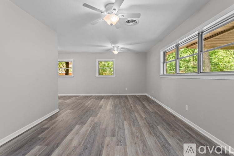 A spacious room with wood flooring and a ceiling fan.