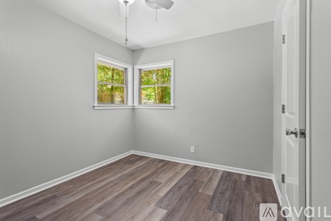 A room with wooden flooring and a window with a view of trees.