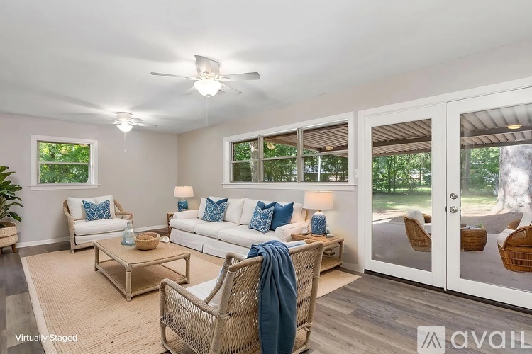 A living room with a white couch, a wicker chair, and a rug.
