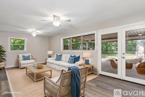 A living room with a white couch, a wicker chair, and a rug.