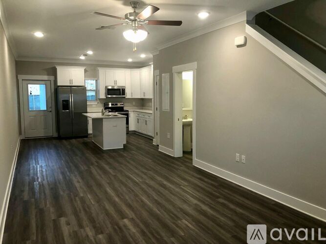 A spacious kitchen with wood flooring and a ceiling fan.