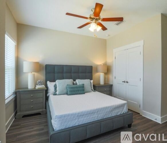 A bedroom with a bed, nightstand, and a ceiling fan.