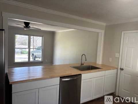 A kitchen with white cabinets and a wooden countertop.
