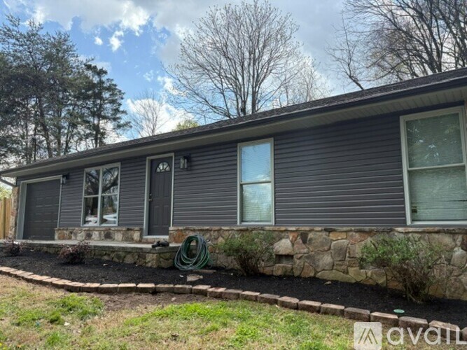 A house with a grey siding and a stone foundation.