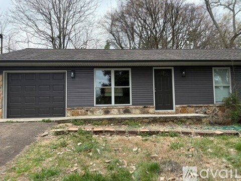 A house with a grey garage door and a stone step leading to the entrance.
