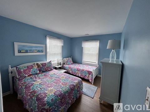 A bedroom with two beds and a nightstand.