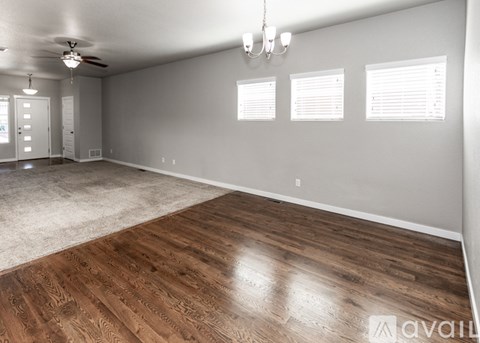 A spacious room with wood flooring and a ceiling fan.