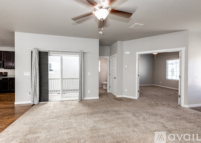A spacious living room with a ceiling fan and carpeted floor.