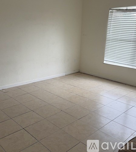 A room with a tiled floor and a window with blinds.