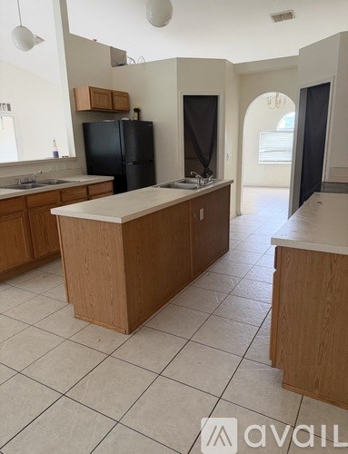 A kitchen with a black refrigerator and wooden cabinets.
