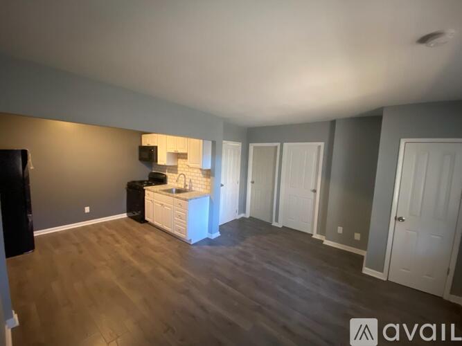 A room with a wooden floor and a cabinet with a sink.