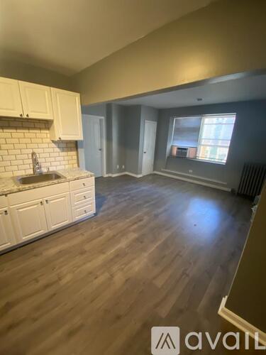 A kitchen with white cabinets and a wooden floor.