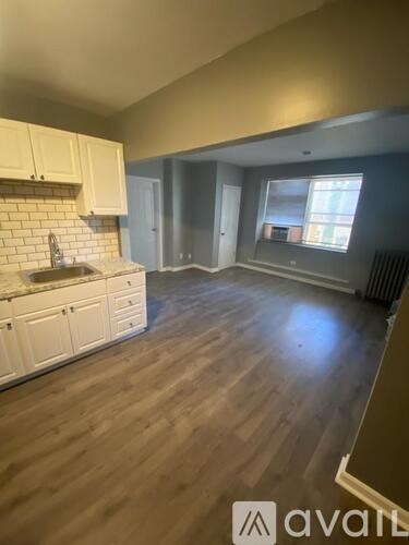 A kitchen with white cabinets and a wooden floor.