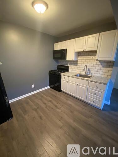 A kitchen with wooden floors and white cabinets.