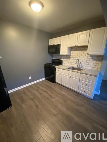 A kitchen with wooden floors and white cabinets.