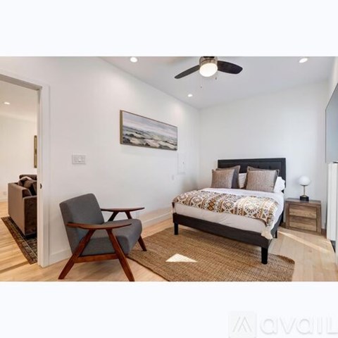 A bedroom with a bed, chair, and painting on the wall.