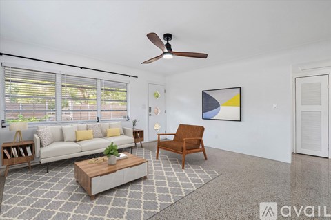 A living room with a white couch, a wooden chair, and a coffee table.