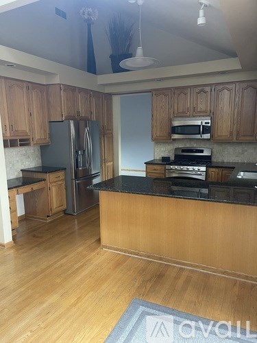 A kitchen with wooden cabinets and black countertops.