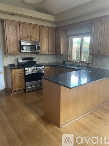 A kitchen with wooden cabinets and a black countertop.