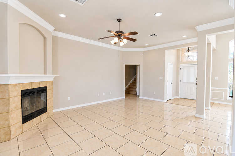 A spacious living room with a fireplace and a ceiling fan.