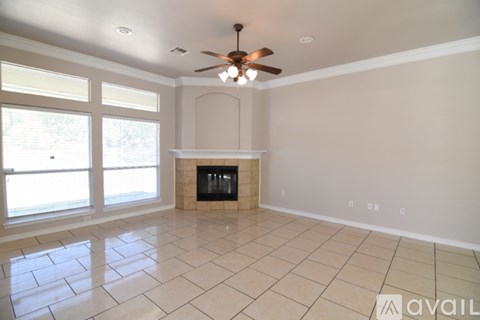 A spacious living room with a fireplace and a ceiling fan.