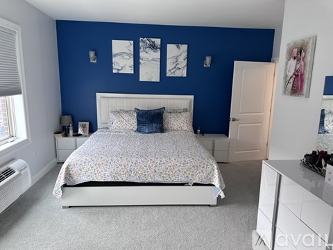 A bedroom with a bed, nightstands, and a window.