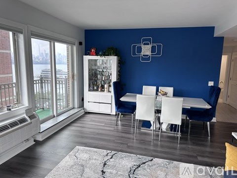 A dining room with a white table and chairs, a blue couch, and a white cabinet with glass doors.