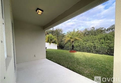 A balcony with a view of a green lawn and trees.