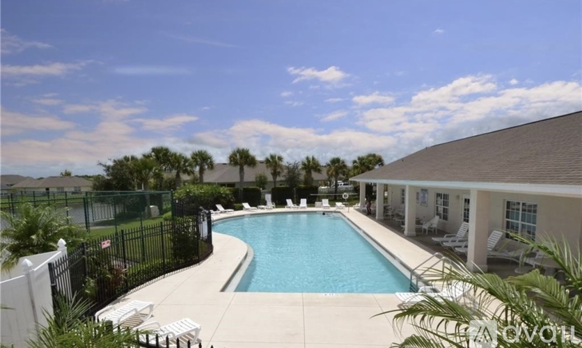 A pool surrounded by a black fence and a house.