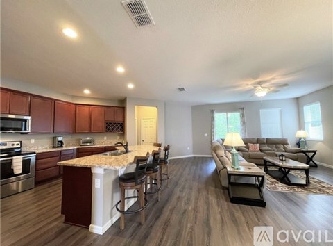 A modern kitchen with a bar area and a living room with a couch and chairs.