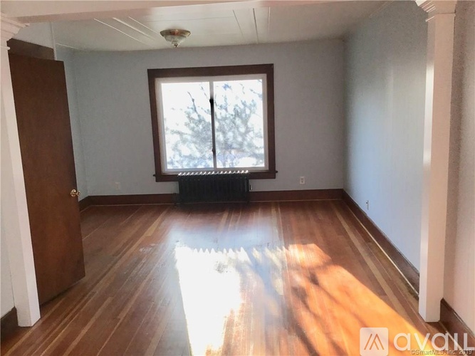 A room with wooden floors and a window with a view of trees.