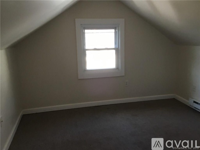 A room with a window and a carpeted floor.