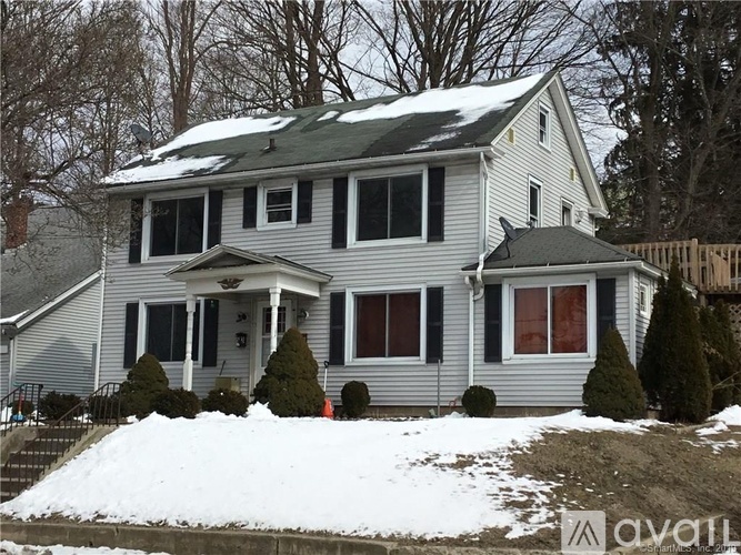 A house with a grey roof and white siding with snow on the ground.