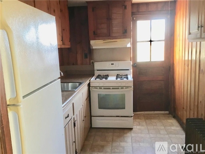 A kitchen with a white fridge, white stove, and wooden cabinets.