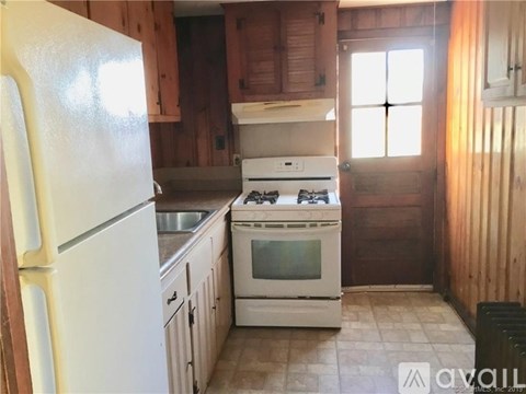 A kitchen with a white fridge, white stove, and wooden cabinets.