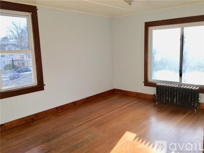A room with wooden floors and two windows.