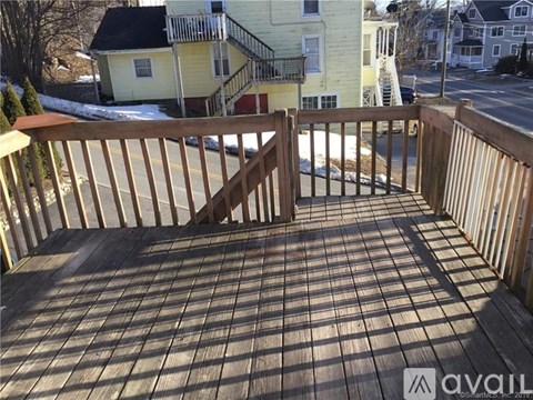 A wooden deck with a railing and a view of the street and houses.