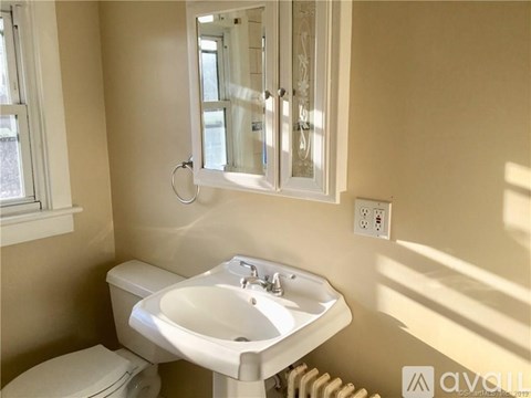 A white sink in a bathroom with a toilet and a mirror.