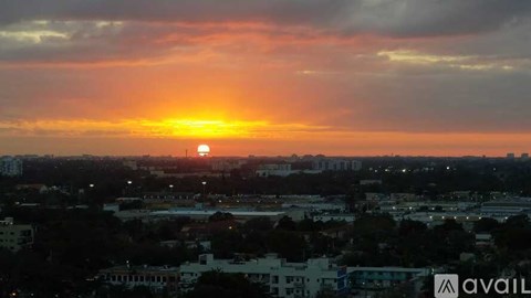 A sunset over a cityscape with buildings and trees.