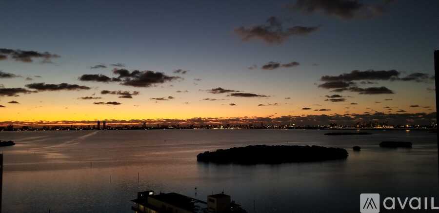 A sunset view over a body of water with a city skyline in the distance.