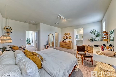 A bedroom with a large bed and a desk with a chair.