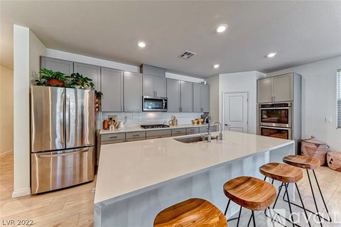 A modern kitchen with a stainless steel refrigerator and wooden bar stools.