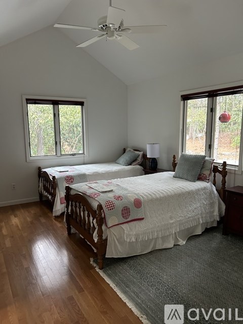 A bedroom with two beds and a ceiling fan.