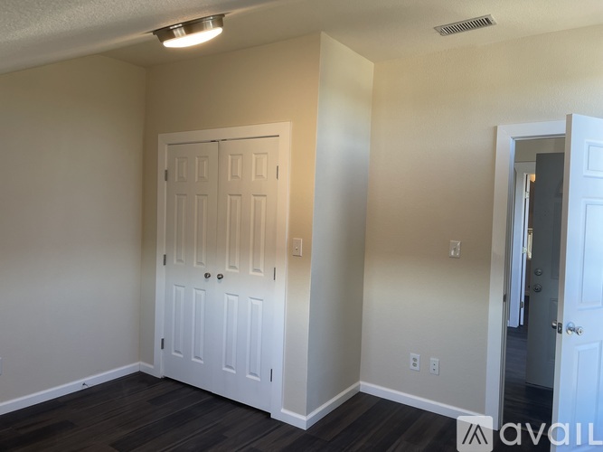 A room with a white door and a wooden floor.