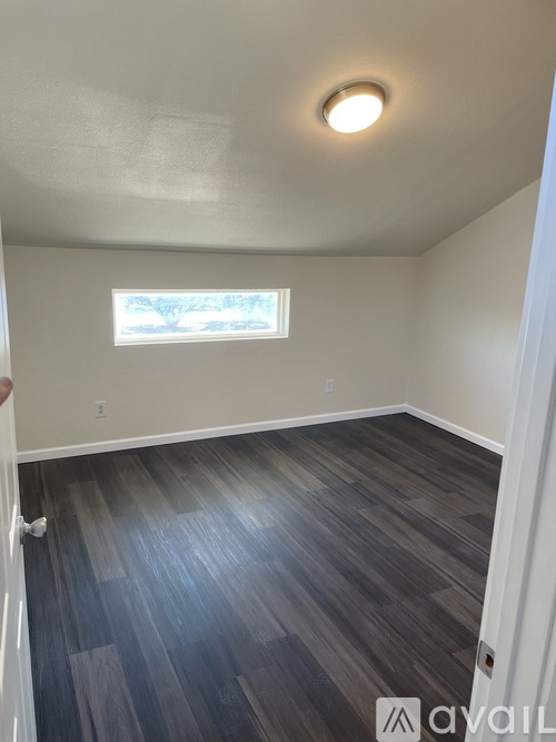 A room with a window and wooden flooring.