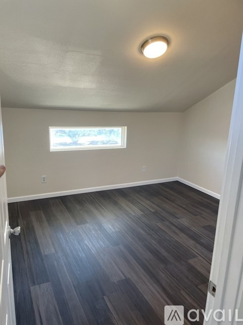 A room with a window and wooden flooring.